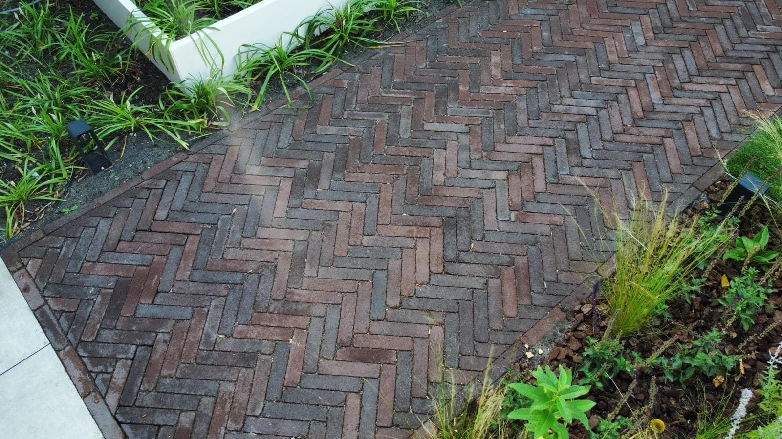 Sierbestrating in visgraatverband met borders en tuinverlichting