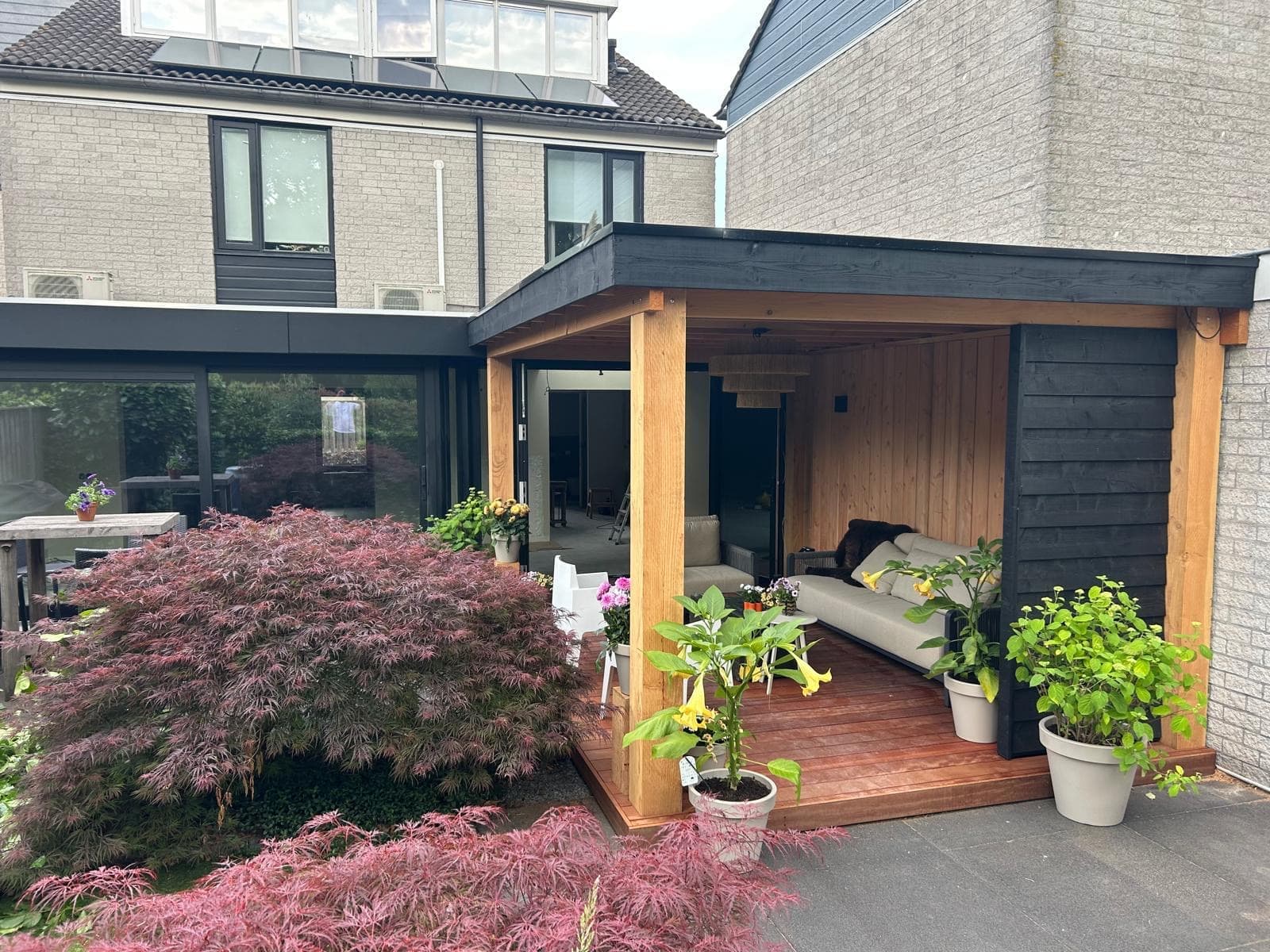 Wooden veranda attached to house with lounge sofa and Japanese maple