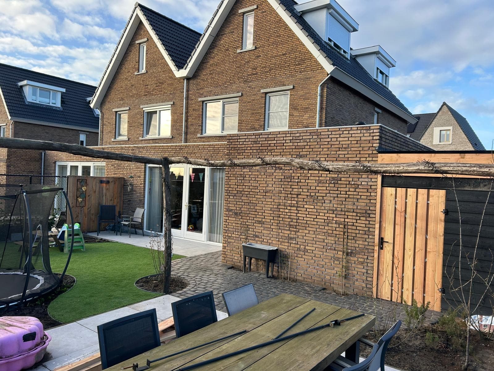 Kindvriendelijke achtertuin met kunstgras en houten pergola