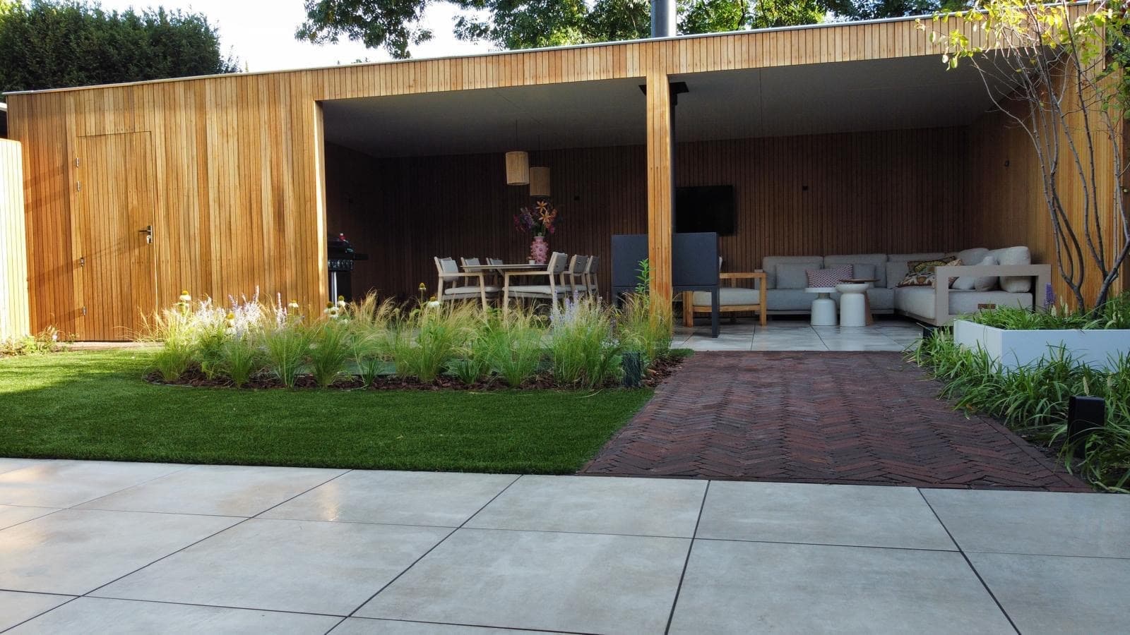 Luxury wooden outdoor living room with lounge, dining area and grasses