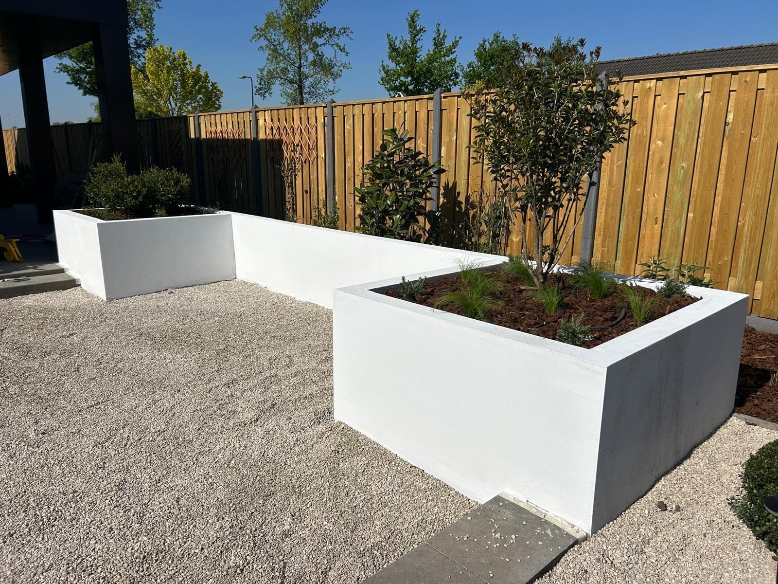 White rendered planters with gravel and wooden fence