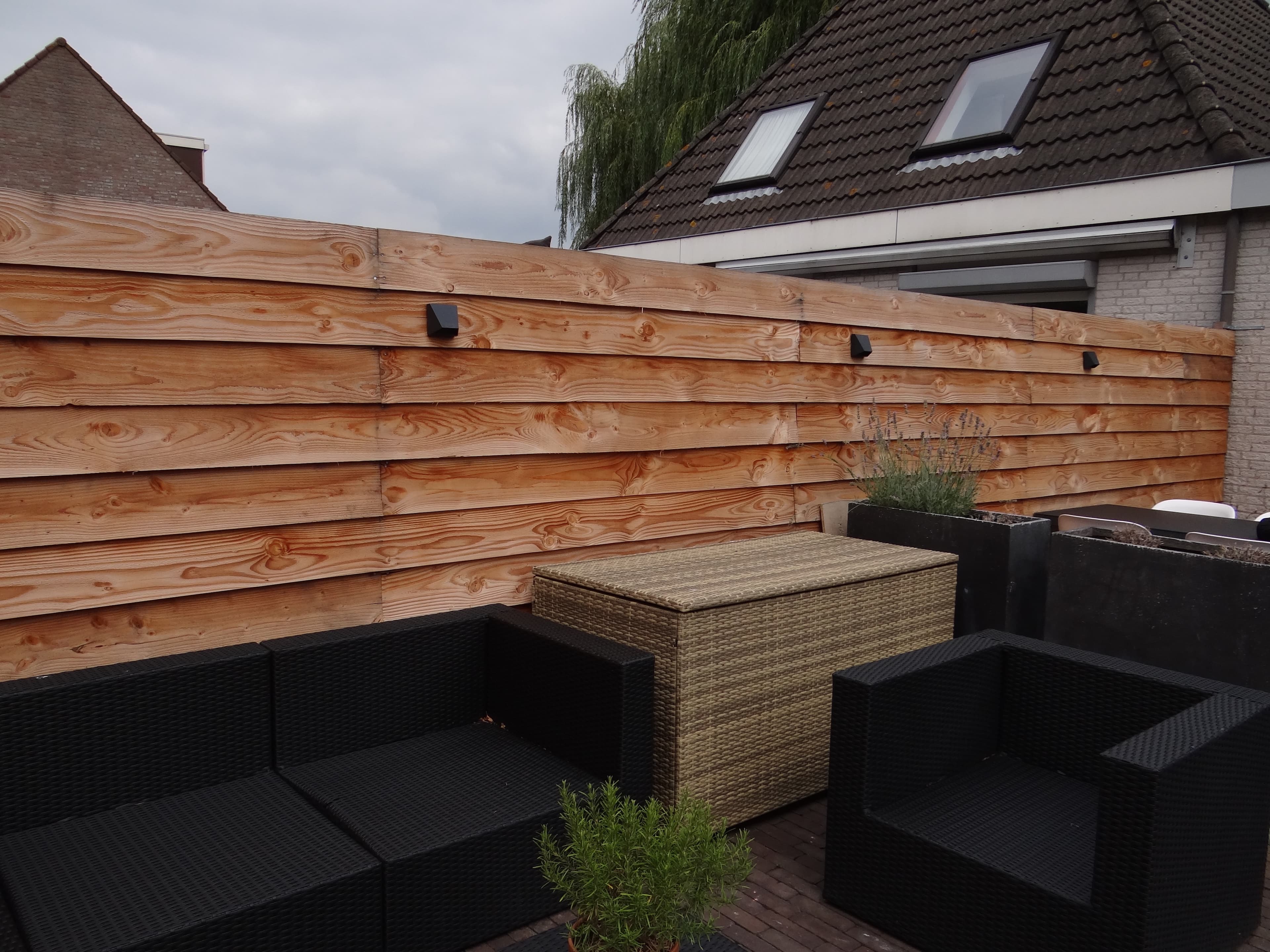 Houten schutting met tuinverlichting boven loungeset op terras