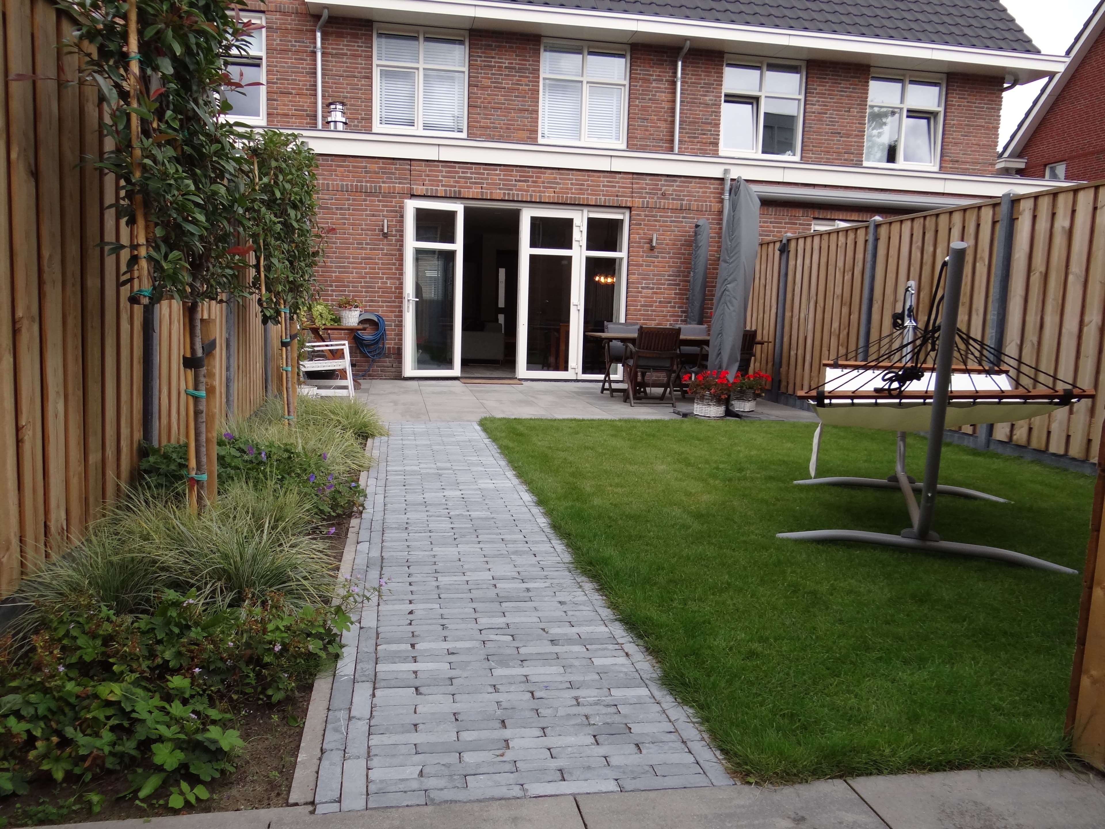 Vers gazon met klinkerpad en groene borders in nieuwbouwtuin